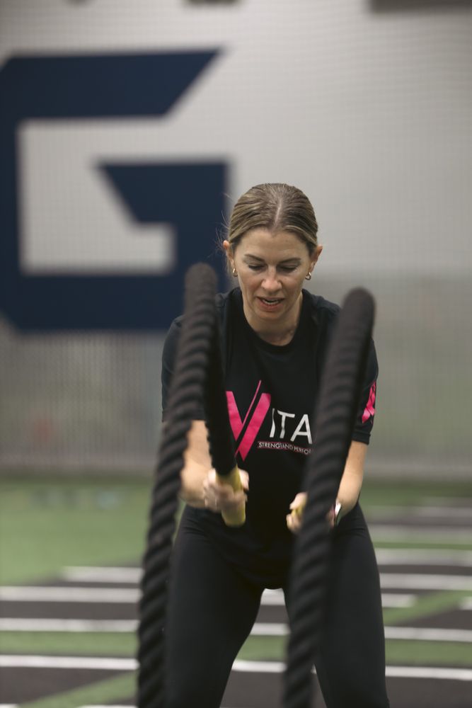 Smiling VITAL member holding dumbbells between sets of small group strength training